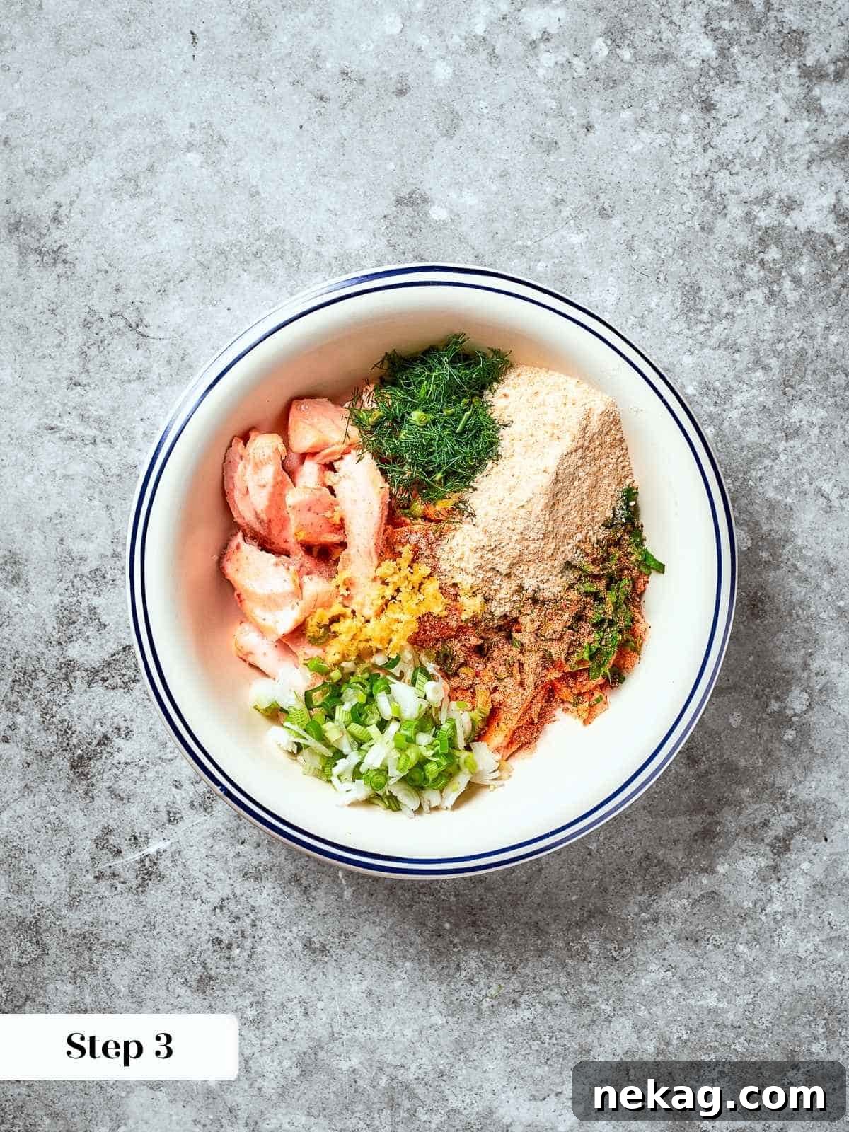 Mixing bowl filled with salmon, herbs, and seasoning before adding the egg.