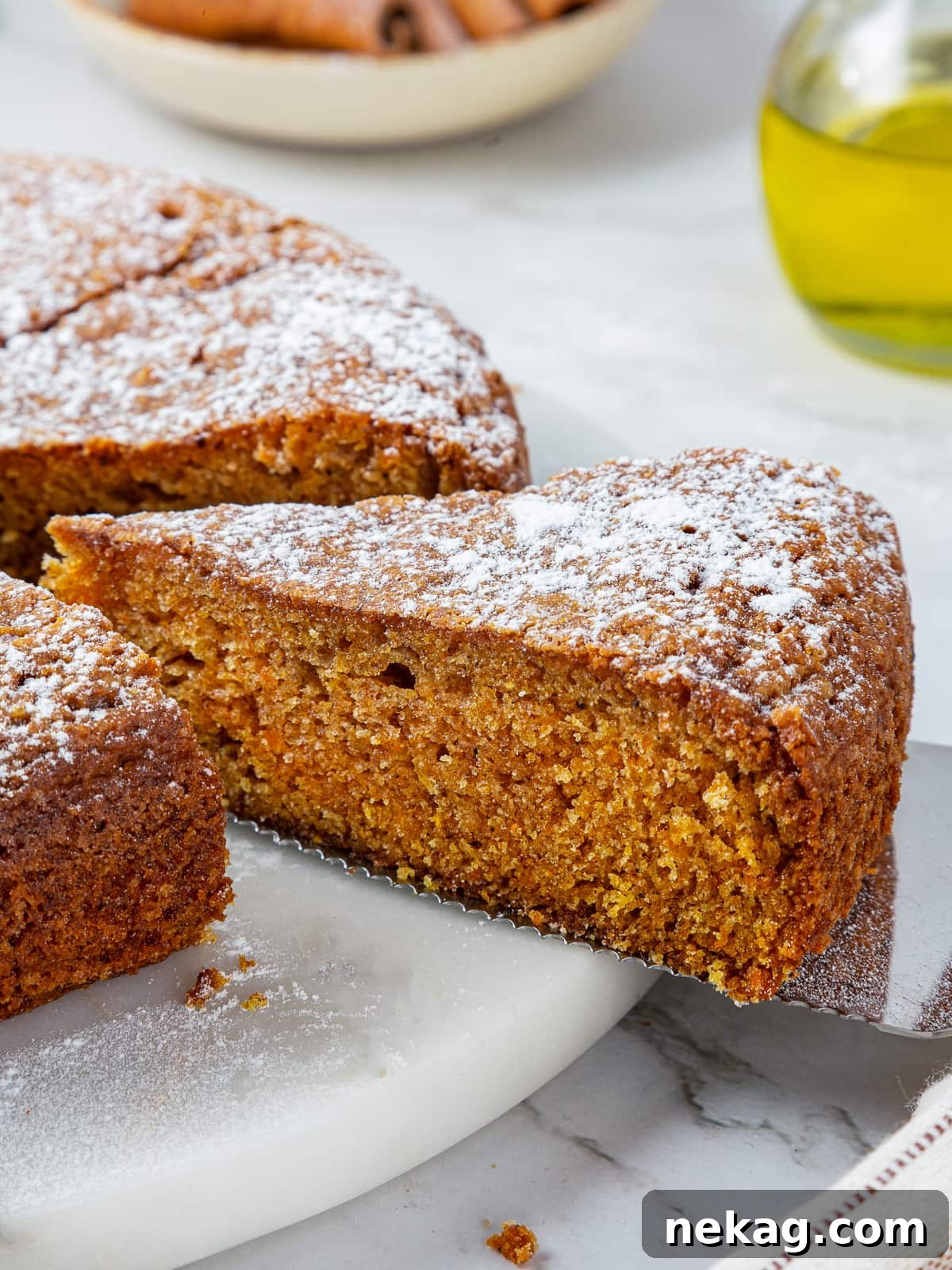 Mediterranean Pumpkin Delight 12 A full, beautifully baked pumpkin cake, elegantly presented on a white ceramic cake stand, with several slices already cut and ready for sharing.