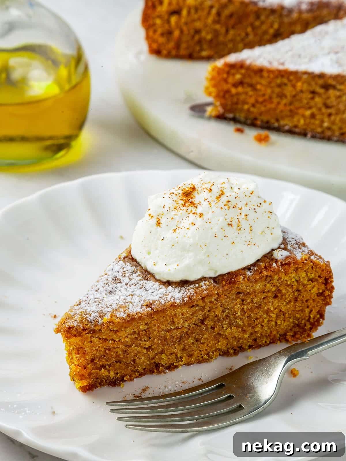 Mediterranean Pumpkin Delight 13 One generous, enticing piece of spiced pumpkin cake elegantly resting on a pristine white plate, with a fork positioned nearby, ready to be enjoyed.