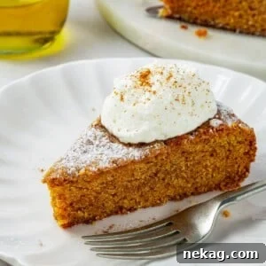 A fork poised next to a soft, inviting slice of pumpkin cake on a dessert plate, with crumbs delicately falling onto the table.