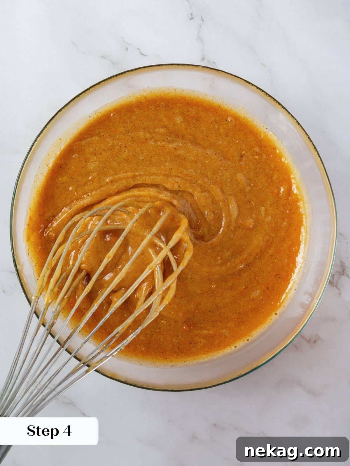 Mediterranean Pumpkin Delight 8 A luscious, spiced pumpkin batter, glossy and vibrant orange, is swirled gently in a large mixing bowl, showcasing its smooth consistency before it's poured into the baking pan.