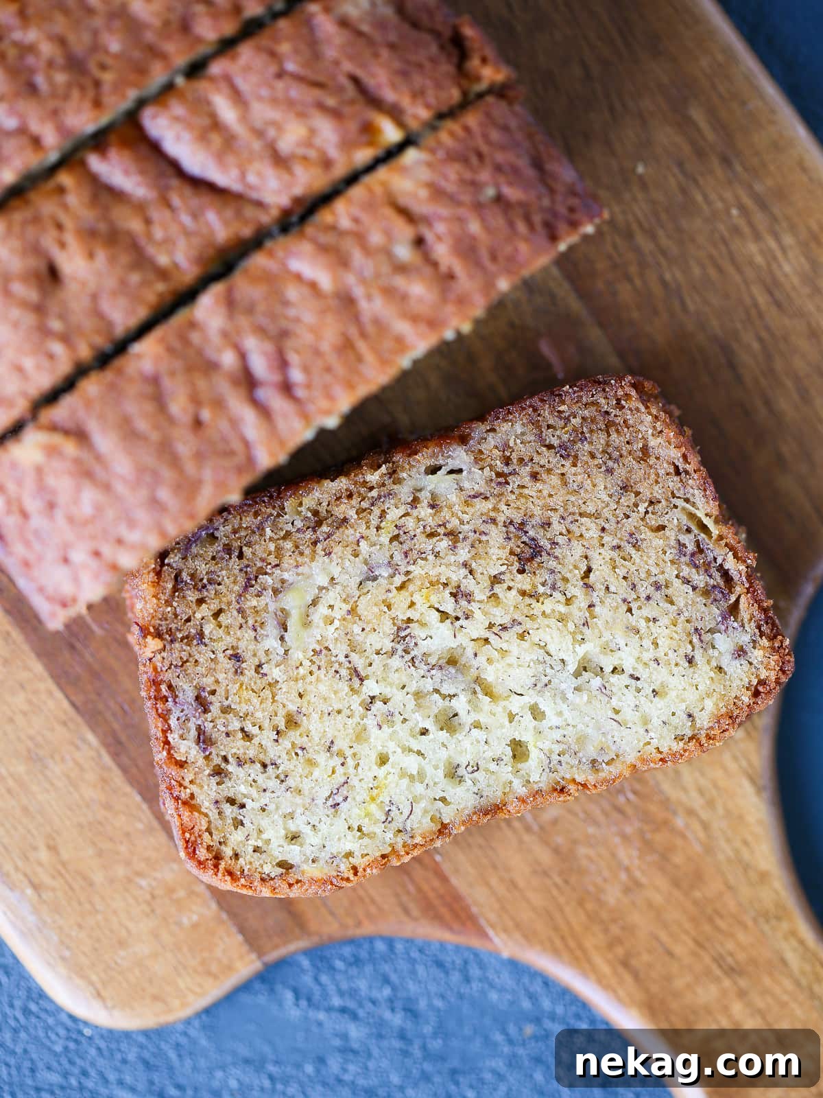Banana bread beautifully sliced on a rustic wooden cutting board, ready to be served.