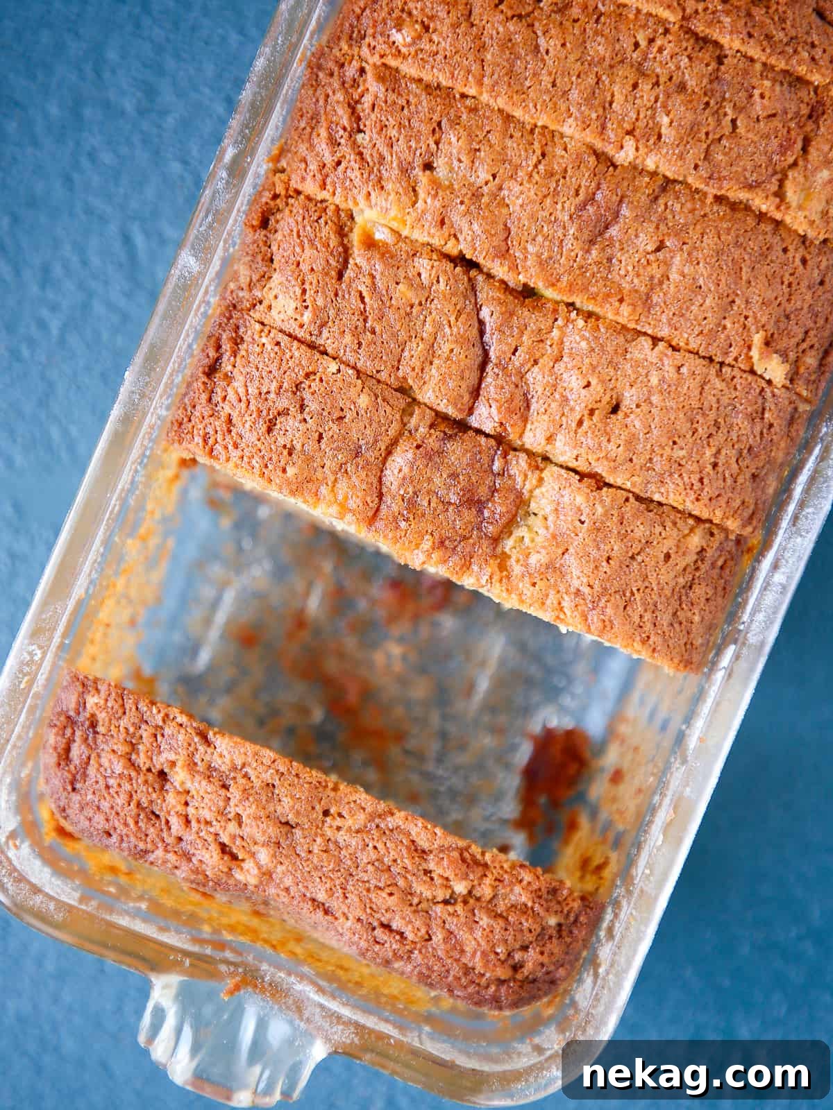 Loaf of banana bread still in the baking dish with visible golden-brown edges, fresh from the oven.