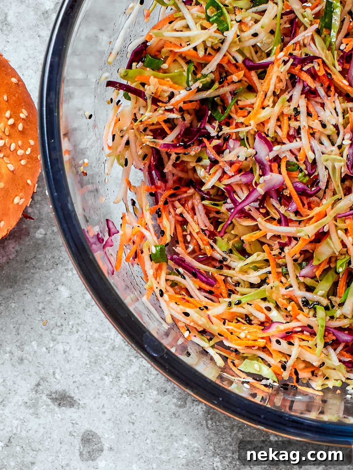 Fresh and Zesty Healthy Broccoli Slaw 2 Healthy broccoli slaw served in a clear glass bowl showing off colors and textures of the dish.