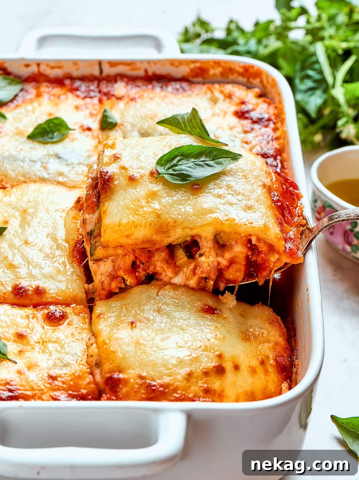 A glorious slice of Zucchini Lasagna being lifted from the pan, showcasing beautifully melted cheese stretching and distinct, firm layers holding together perfectly.