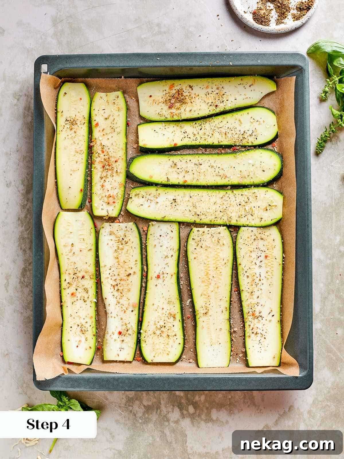 Baking dish filled with neatly arranged, seasoned zucchini planks, glistening and ready for roasting to achieve perfect crispness and moisture removal.