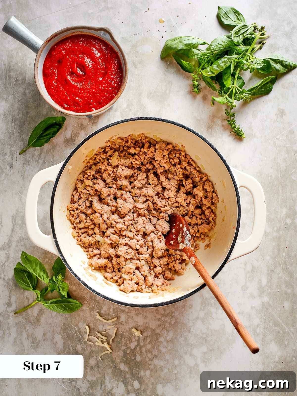 Ground chicken is actively browning in a skillet, developing a rich, golden crust, signifying it's becoming a robust component of the lasagna's tomato meat sauce.