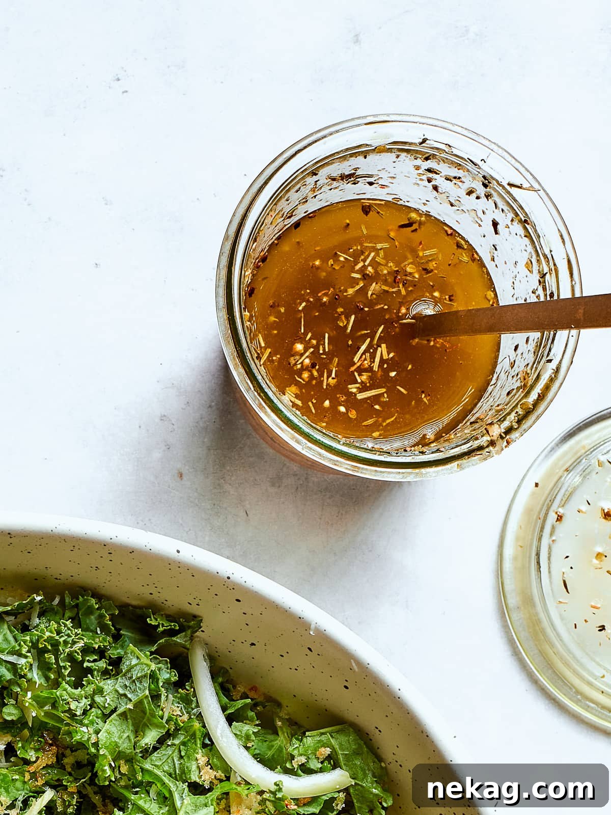 Zesty Homemade Italian Dressing 2 homemade Italian salad dressing with flecks of oregano and cheese, served with a gold spoon.