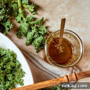 Jar of Italian salad dressing set beside fresh kale leaves on a counter.