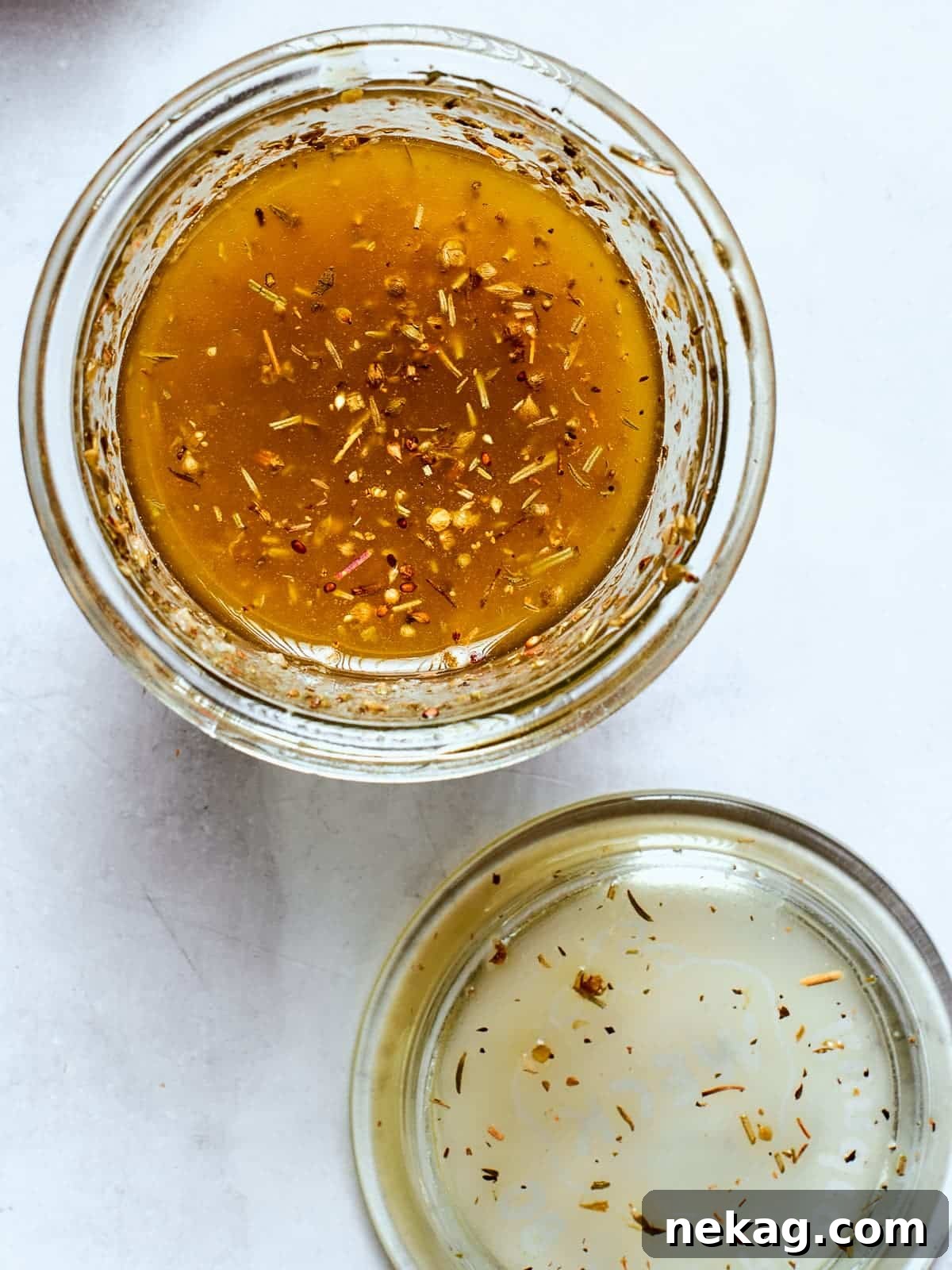 Zesty Homemade Italian Dressing 8 Clear glass jar filled with Italian salad dressing and visible herbs, ready for use.