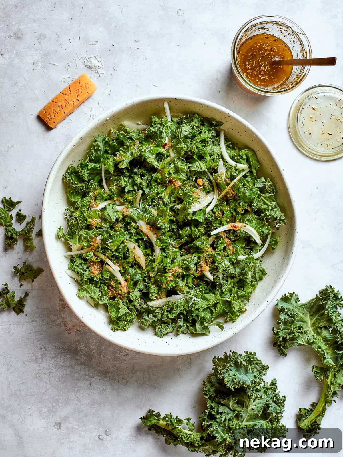 Large serving bowl filled with Tuscan kale salad, onions, parmesan, and breadcrumbs.