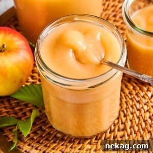 Homemade applesauce in a jar resting on a wicker placemat, surrounded by natural autumn light, inviting a taste.