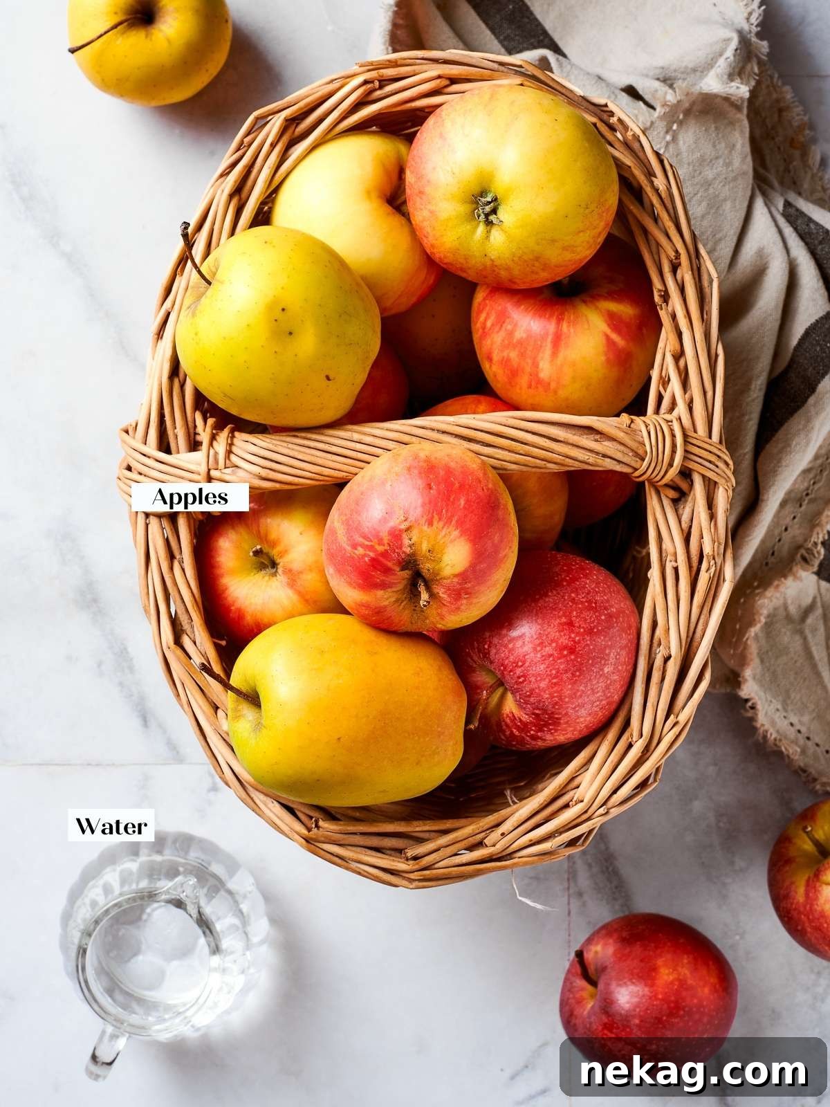 A selection of various apples and simple ingredients laid out on a countertop, ready for making homemade applesauce.