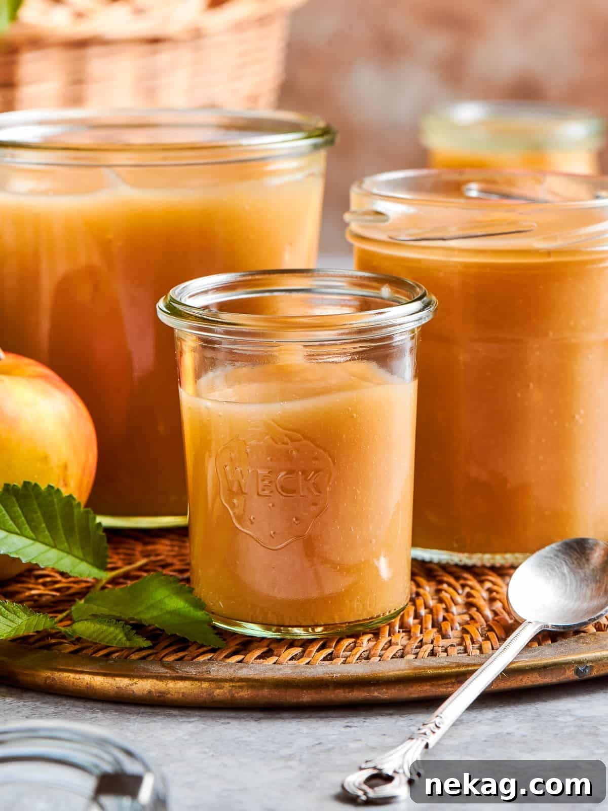 Smooth applesauce presented in a clear jar, showcasing its natural color and readiness to serve with meals.