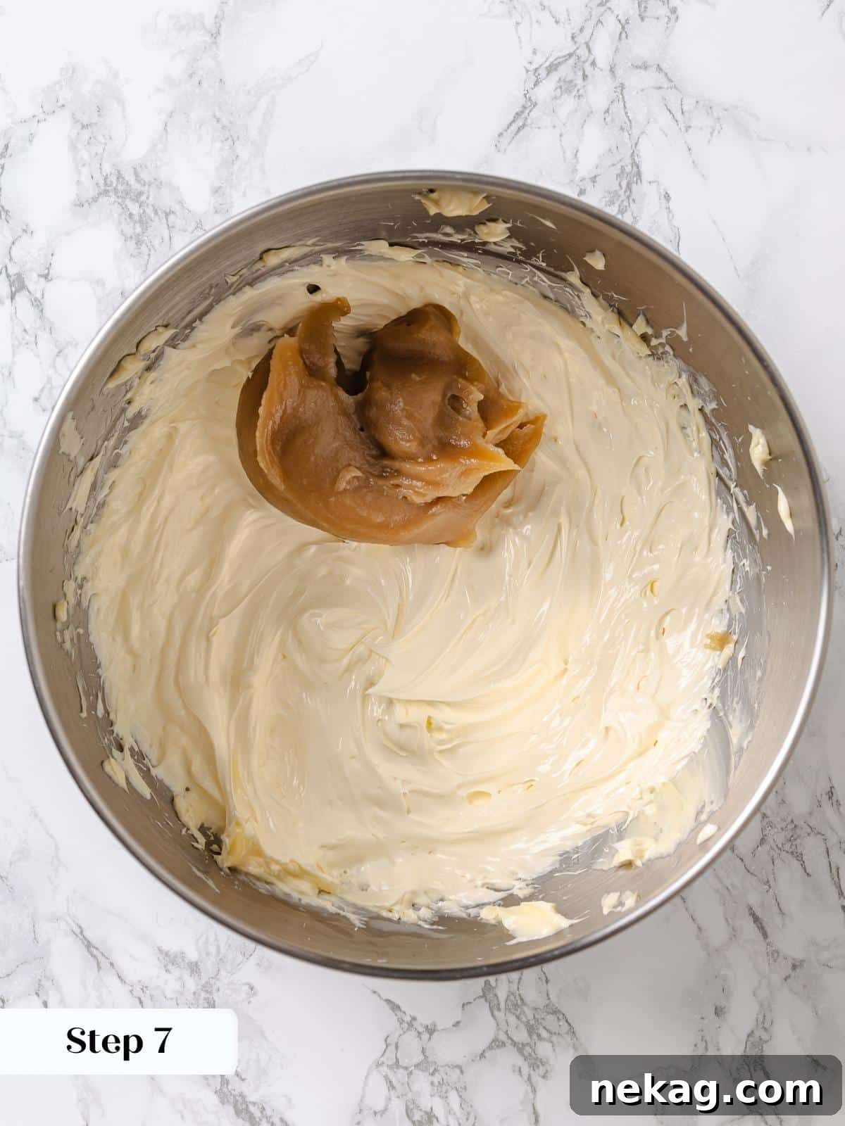 Velvet Maple Glaze 11 The cooled maple mixture is added gradually, spoonful by spoonful, to the whipped butter in the stand mixer bowl.