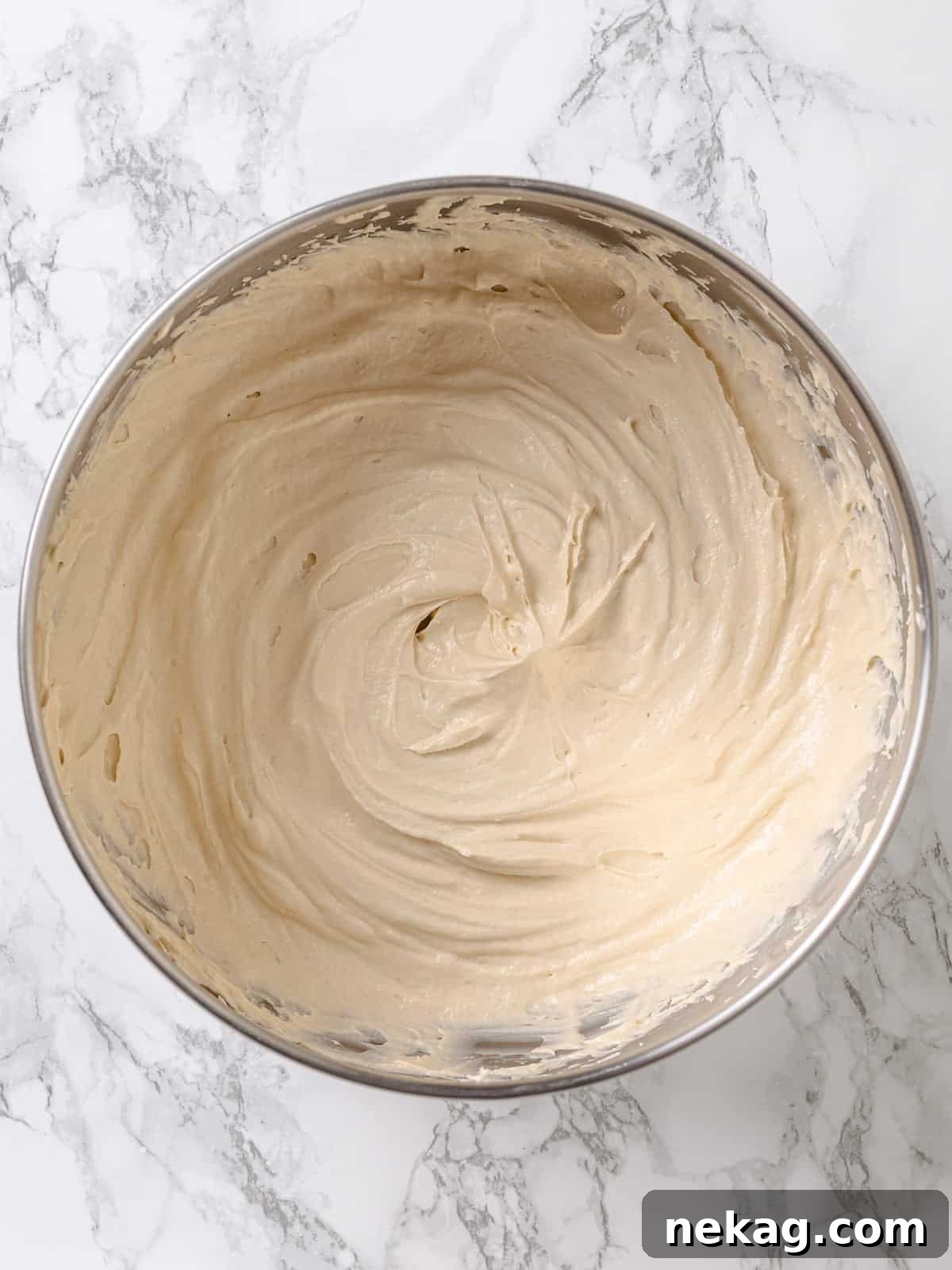 Velvet Maple Glaze 12 A large bowl brimming with freshly made maple frosting, showcasing its fluffy texture and rich maple flavor.