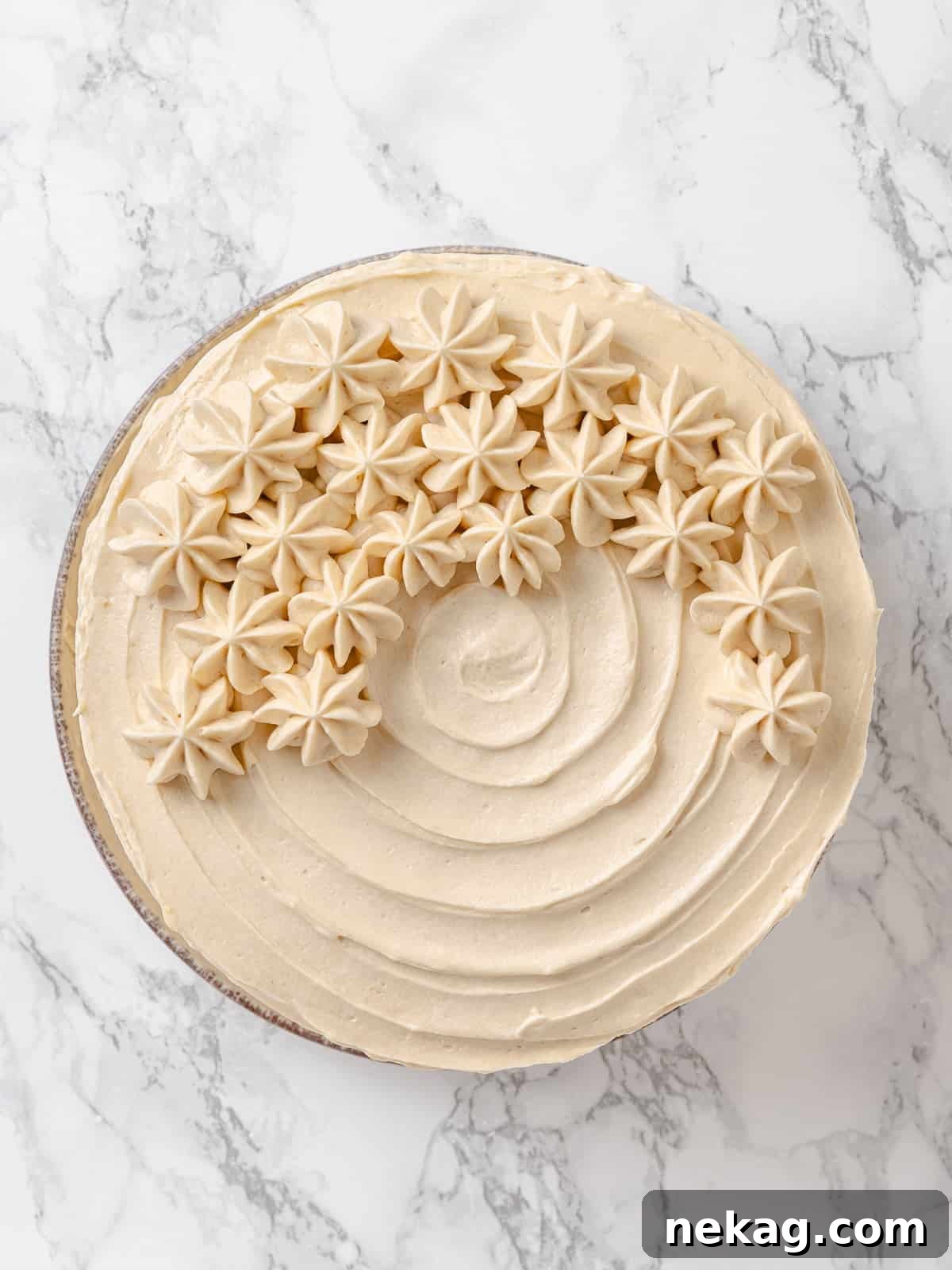 Velvet Maple Glaze 13 Thick swirls of maple frosting generously spread across a cake surface, showing creamy peaks and inviting sweetness.