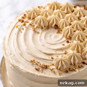 Maple cake decorated with toasted pecans scattered across the frosted top.