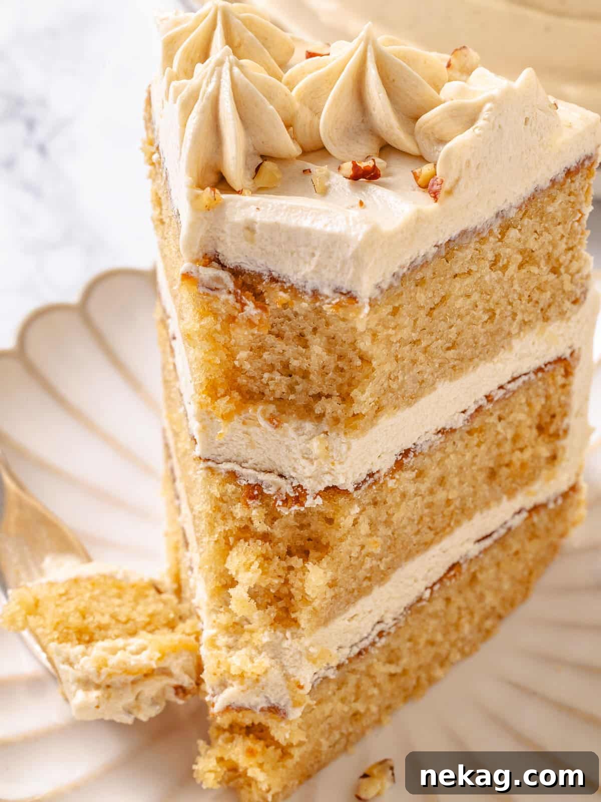 Golden Maple Delight 2 Fork holding a bite of maple cake, revealing three delicate layers with smooth frosting in between.