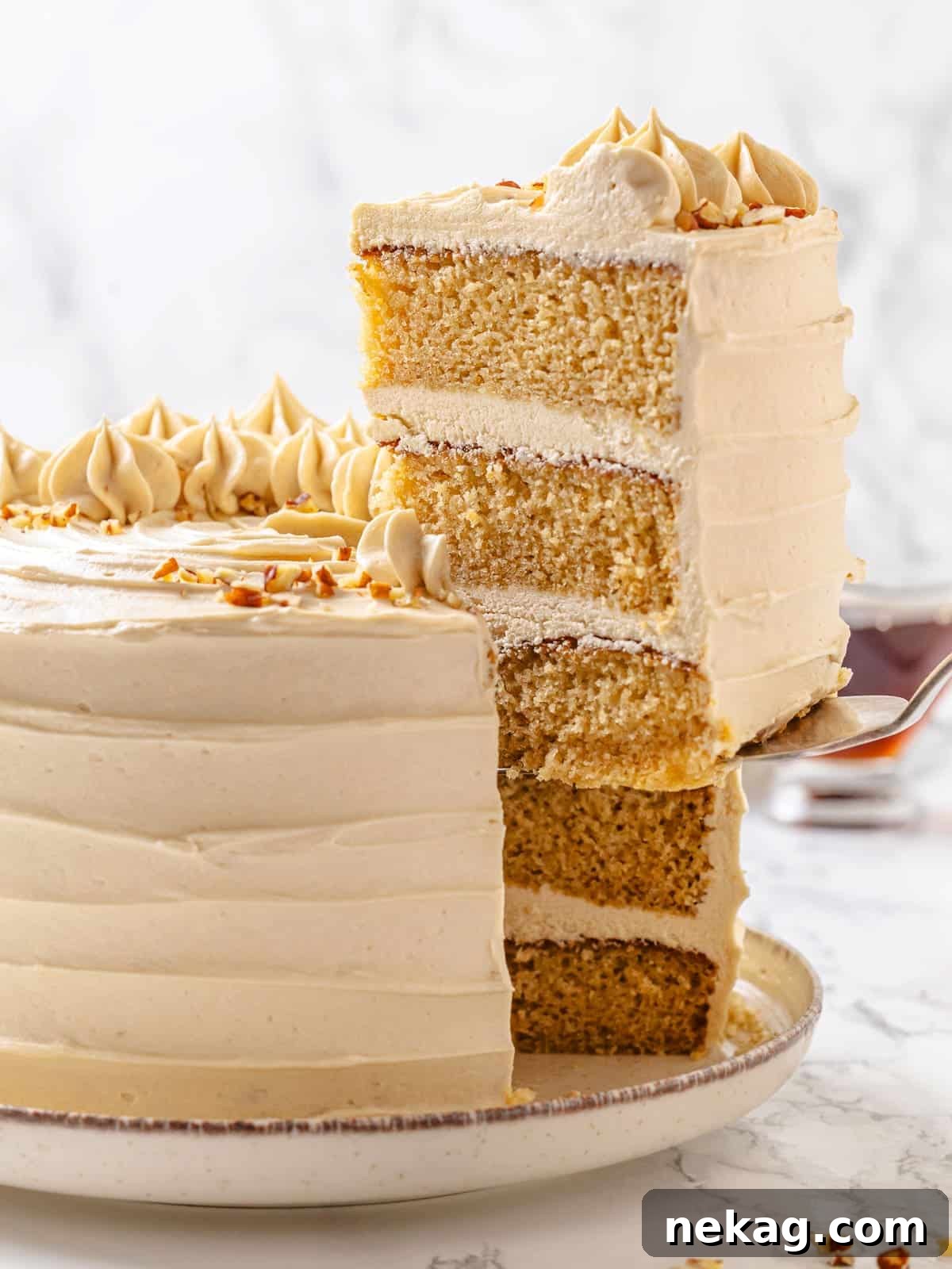 Golden Maple Delight 21 A slice of maple cake being elegantly served, with visible layers of soft cake and fluffy frosting on a serving utensil.