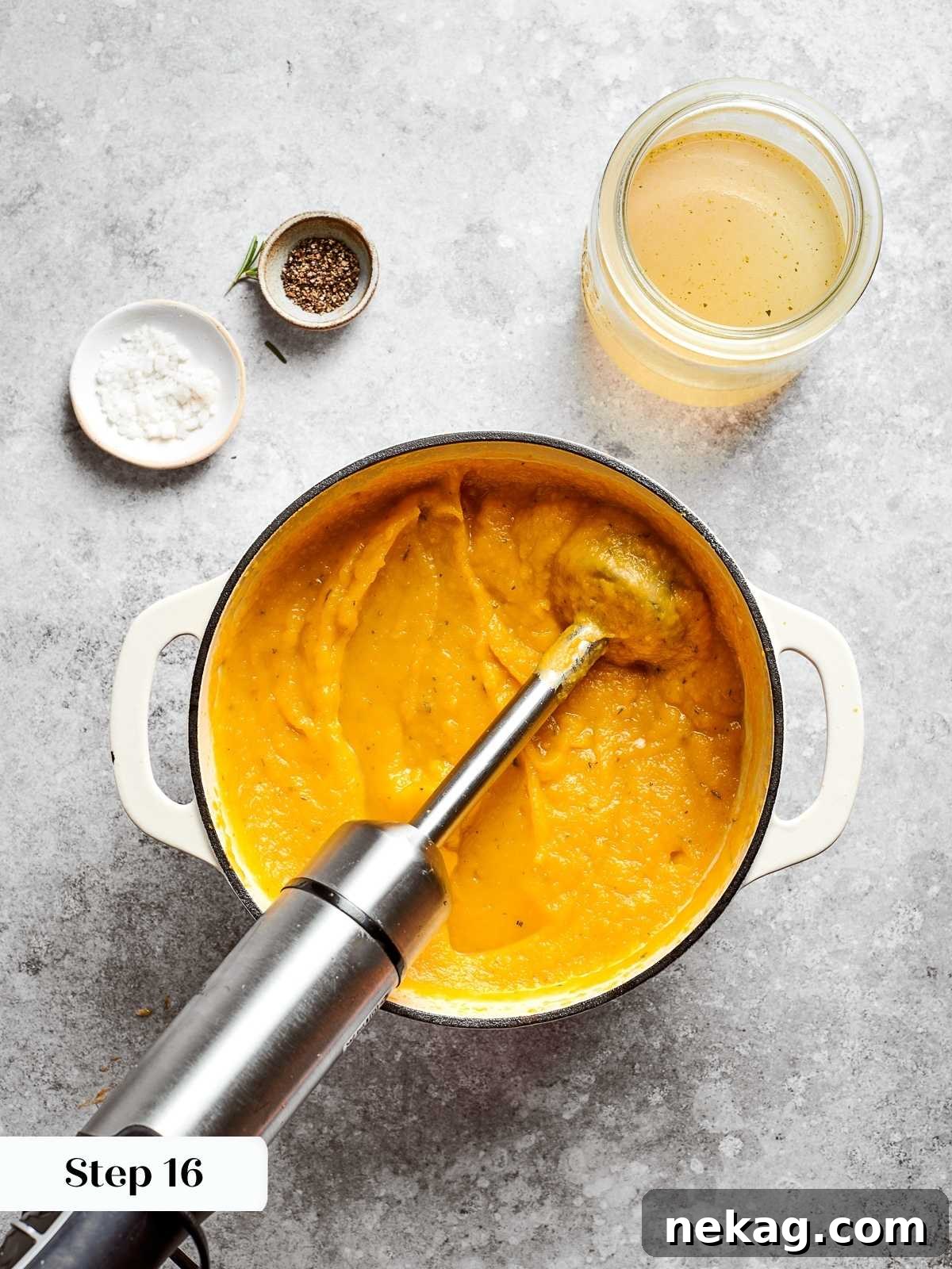 An immersion blender actively pureeing the roasted squash soup directly in the pot, transforming the chunky mixture into a smooth, luxurious, and creamy consistency.