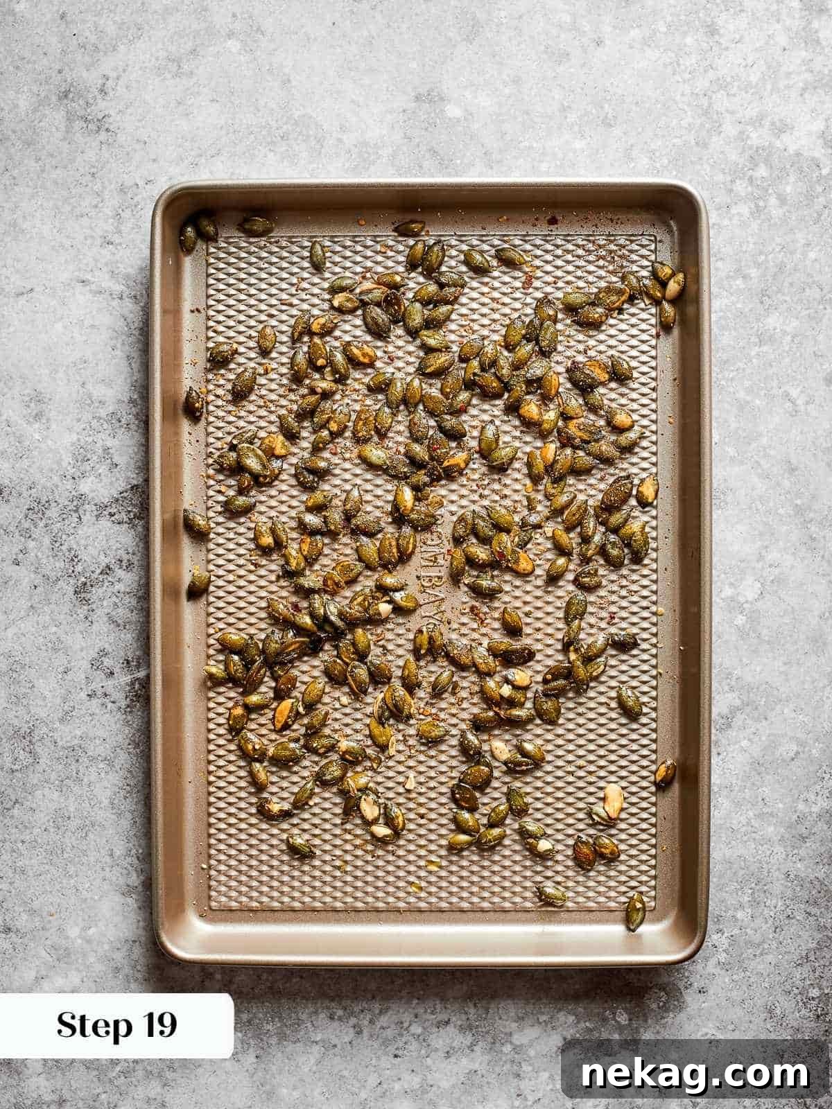 Raw pumpkin seeds (pepitas) evenly spread on a parchment-lined baking tray, glistening with olive oil and spices, ready to be roasted to a golden, crunchy perfection for garnish.