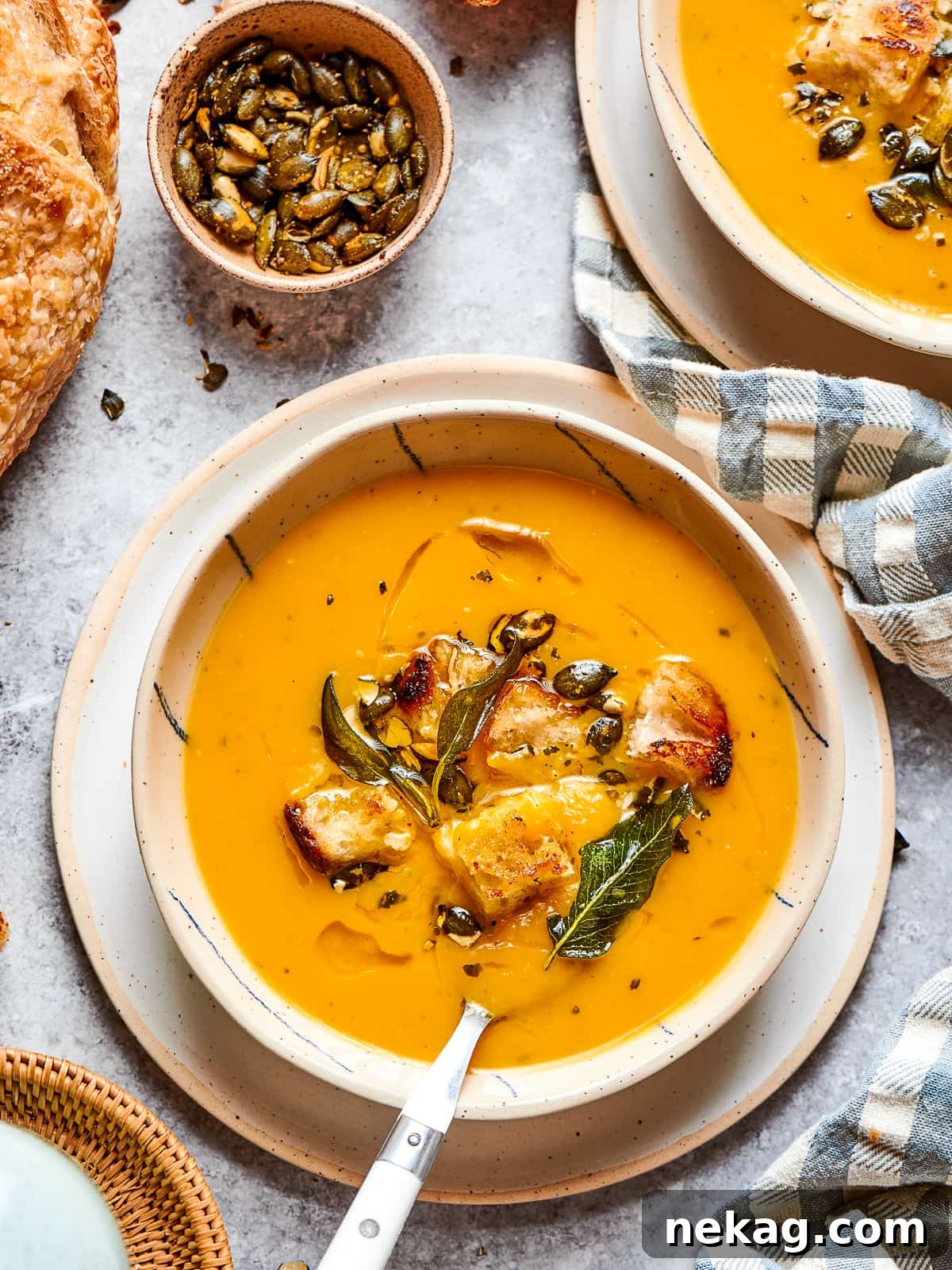 A perfectly portioned bowl of creamy roasted squash soup, elegantly garnished with a light sprinkle of black pepper and delicate fresh herbs, ready to be served and enjoyed as a comforting meal.