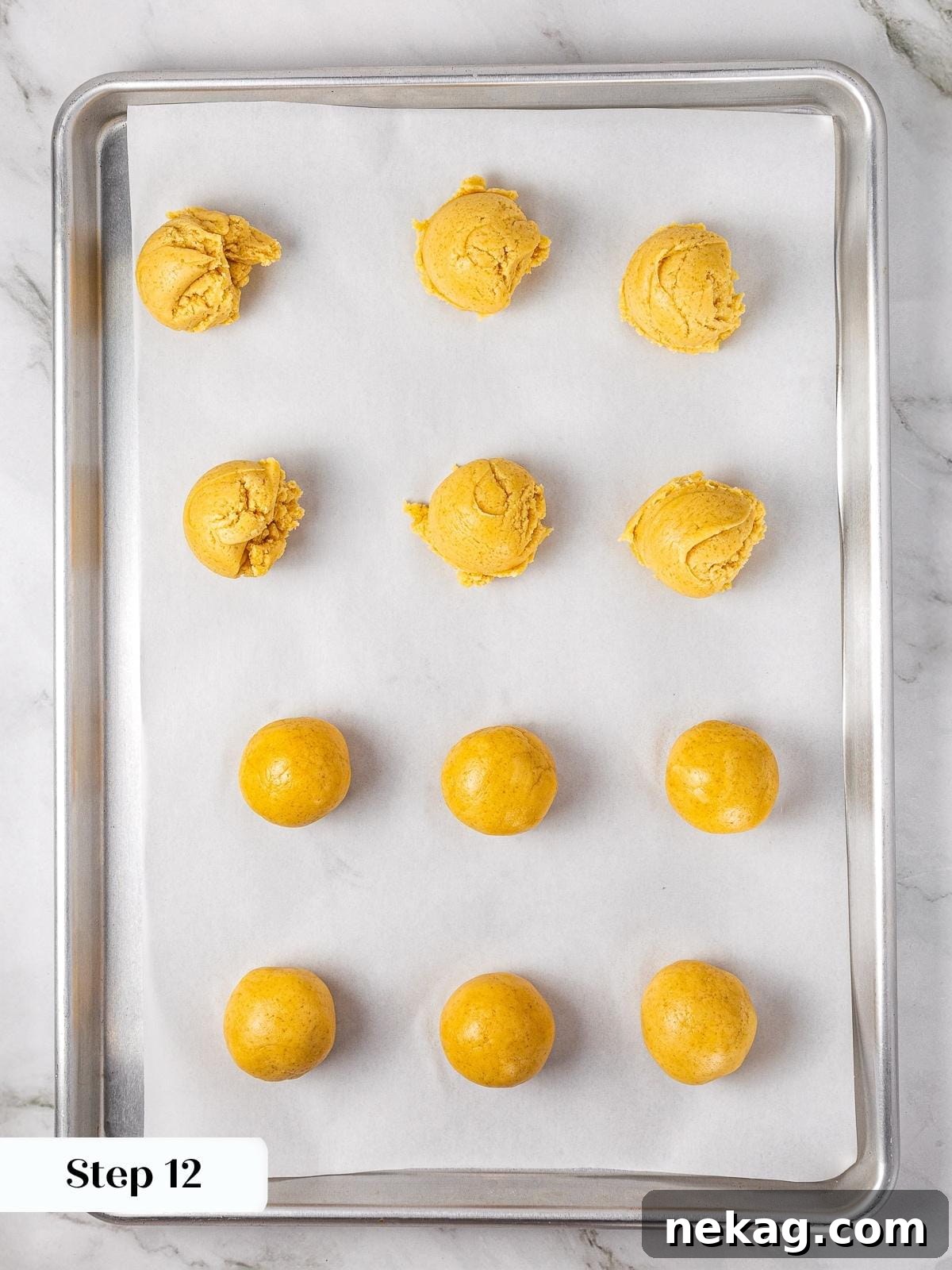 Apple Crumble Cookies 11 Rows of apple pie cookie dough balls resting on parchment paper before being pressed and filled.