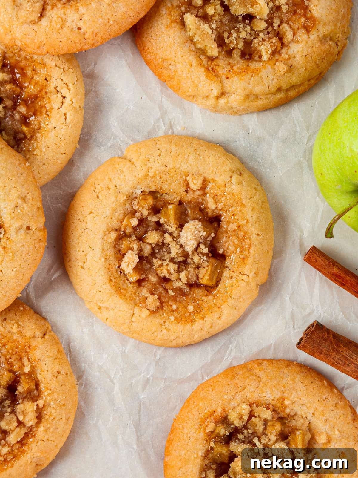 Apple Crumble Cookies 16 Baked apple cookies with visible crumble and caramelized apple filling on a parchment sheet.