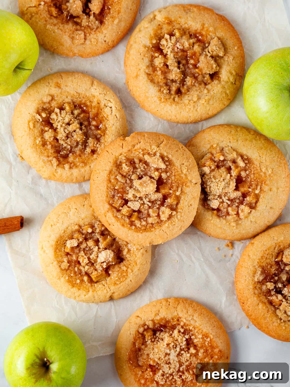 Apple Crumble Cookies 17 Assorted apple pie cookies spread on a table showing golden crumble tops and soft centers.