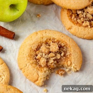 A single apple pie cookie with a bite revealing its chewy brown sugar dough and apple filling.