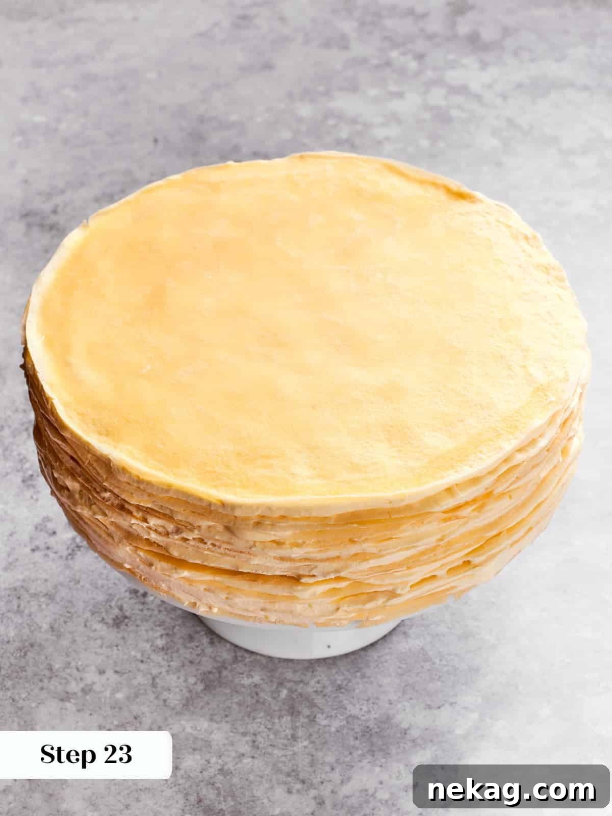 Delicate Layered Crepe Dessert 15 Crepes being layered with crème légère to build the tall mille crepe cake.