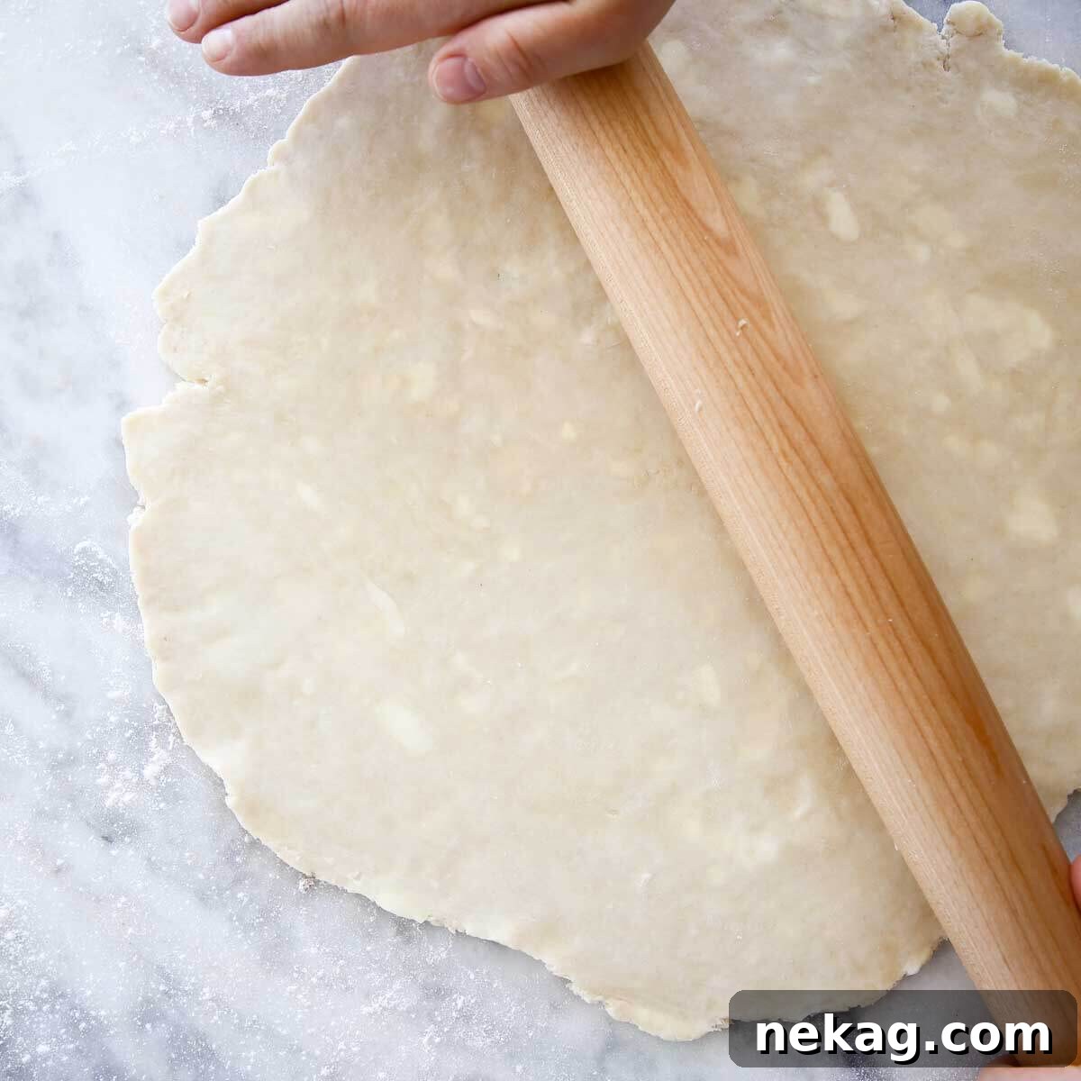 Flaky Butter Crust Perfection 4 Hands rolling out pie dough on a marble surface with a rolling pin.