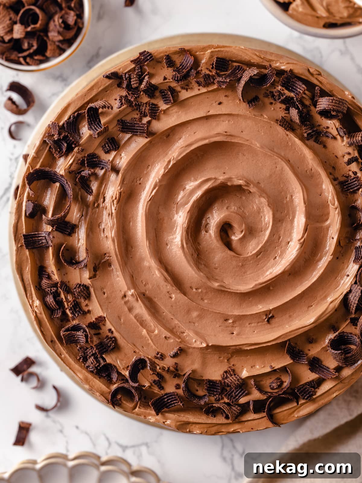 A swirl of chocolate Swiss meringue buttercream topped with tiny chocolate shavings, showcasing its smooth texture.