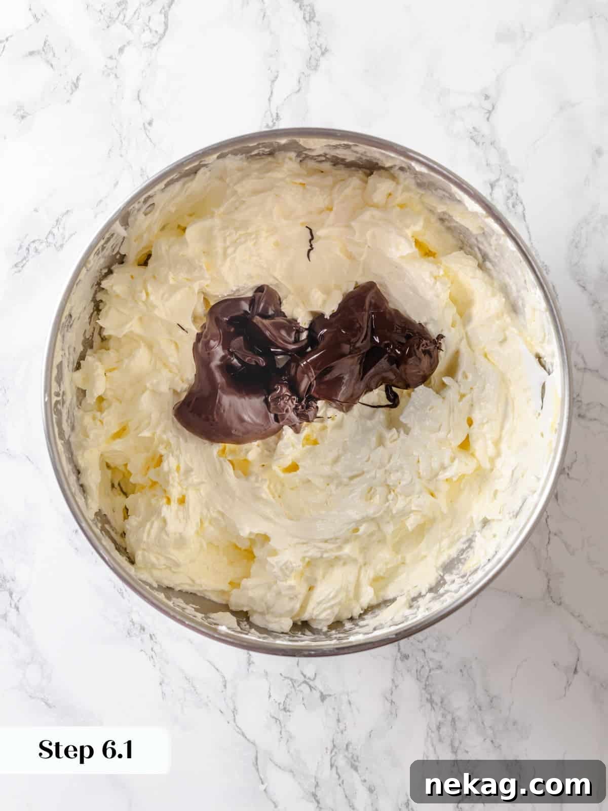 A bowl of buttercream ready as warm melted chocolate is carefully poured in for final mixing.