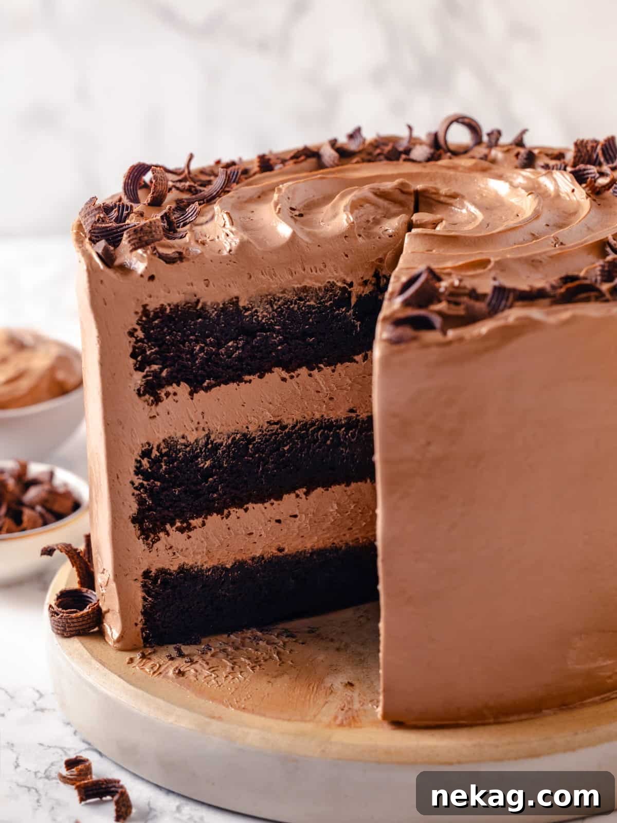 A frosted chocolate cake showing a missing slice and soft buttercream covering every side, ready for serving.