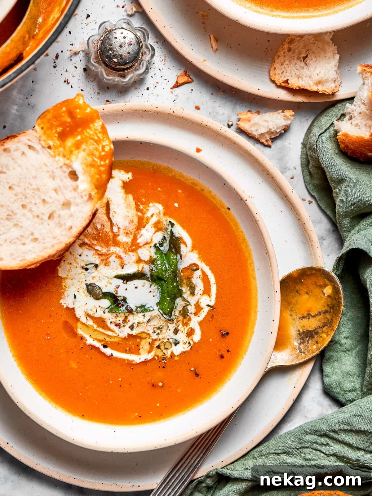 Wholesome Vegan Pumpkin Harvest Soup 10 Pumpkin soup served in an elegant bowl, with soft pieces of torn artisanal bread arranged artfully nearby for dipping.