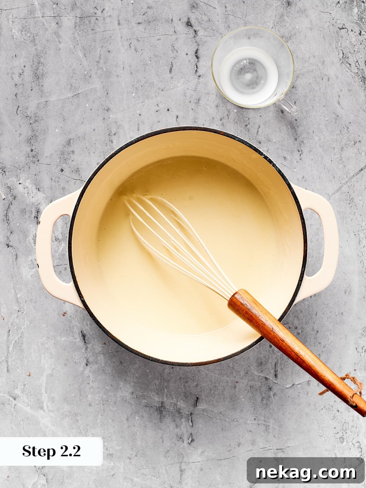 Saucepan with thickening milk and roux whisked until smooth and creamy.