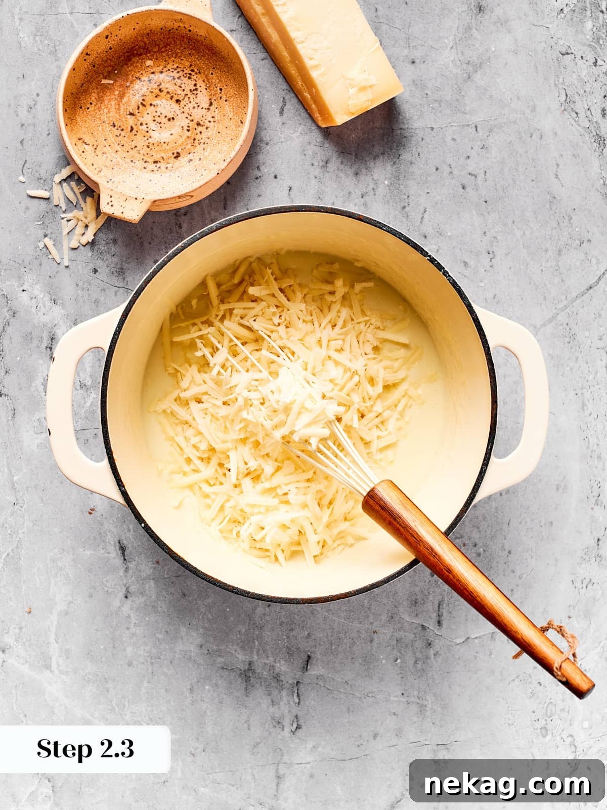Cheese melting into béchamel to create a creamy cheddar sauce.