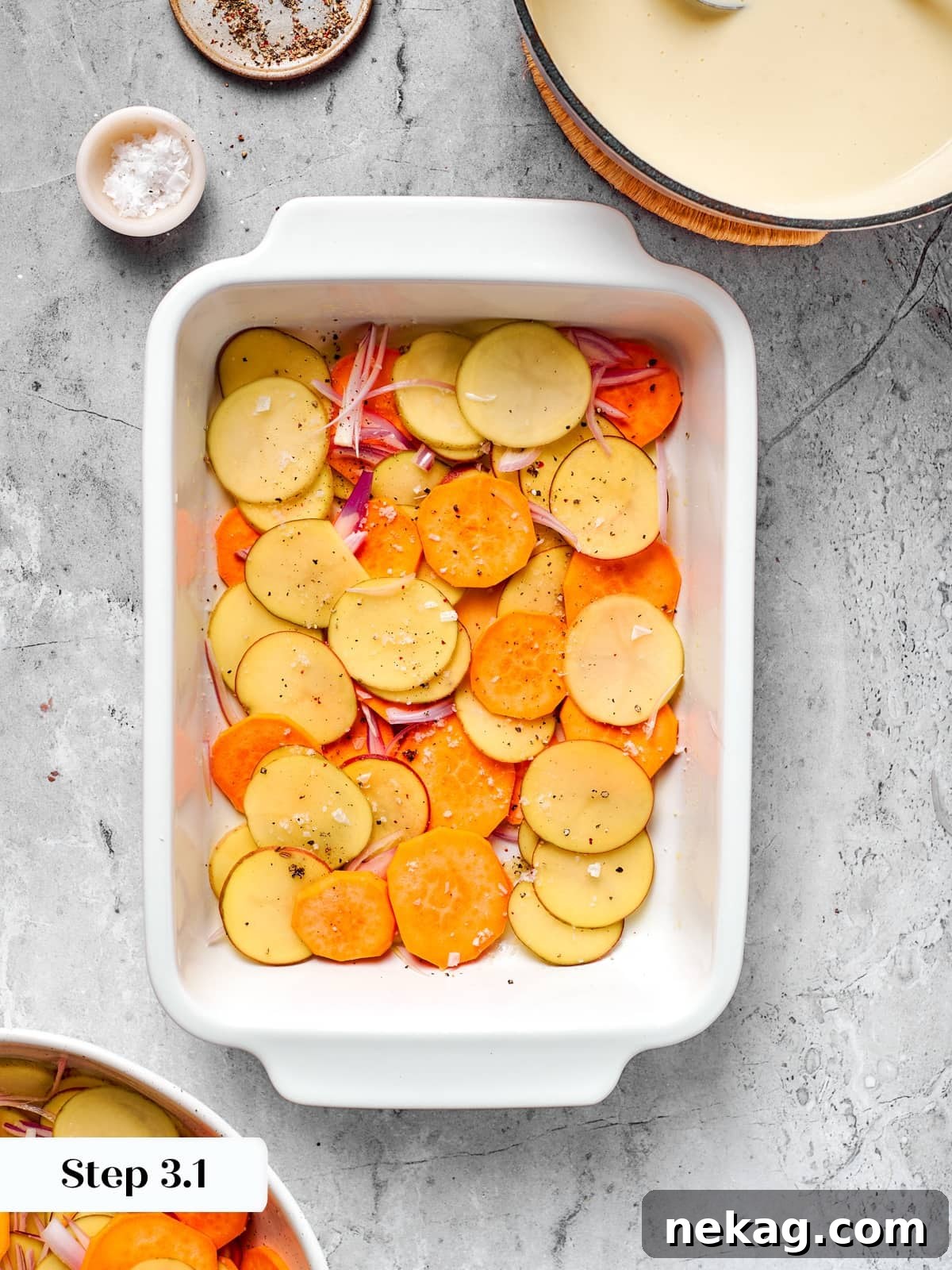 First layer of thin sliced potatoes and shallots arranged in baking dish.