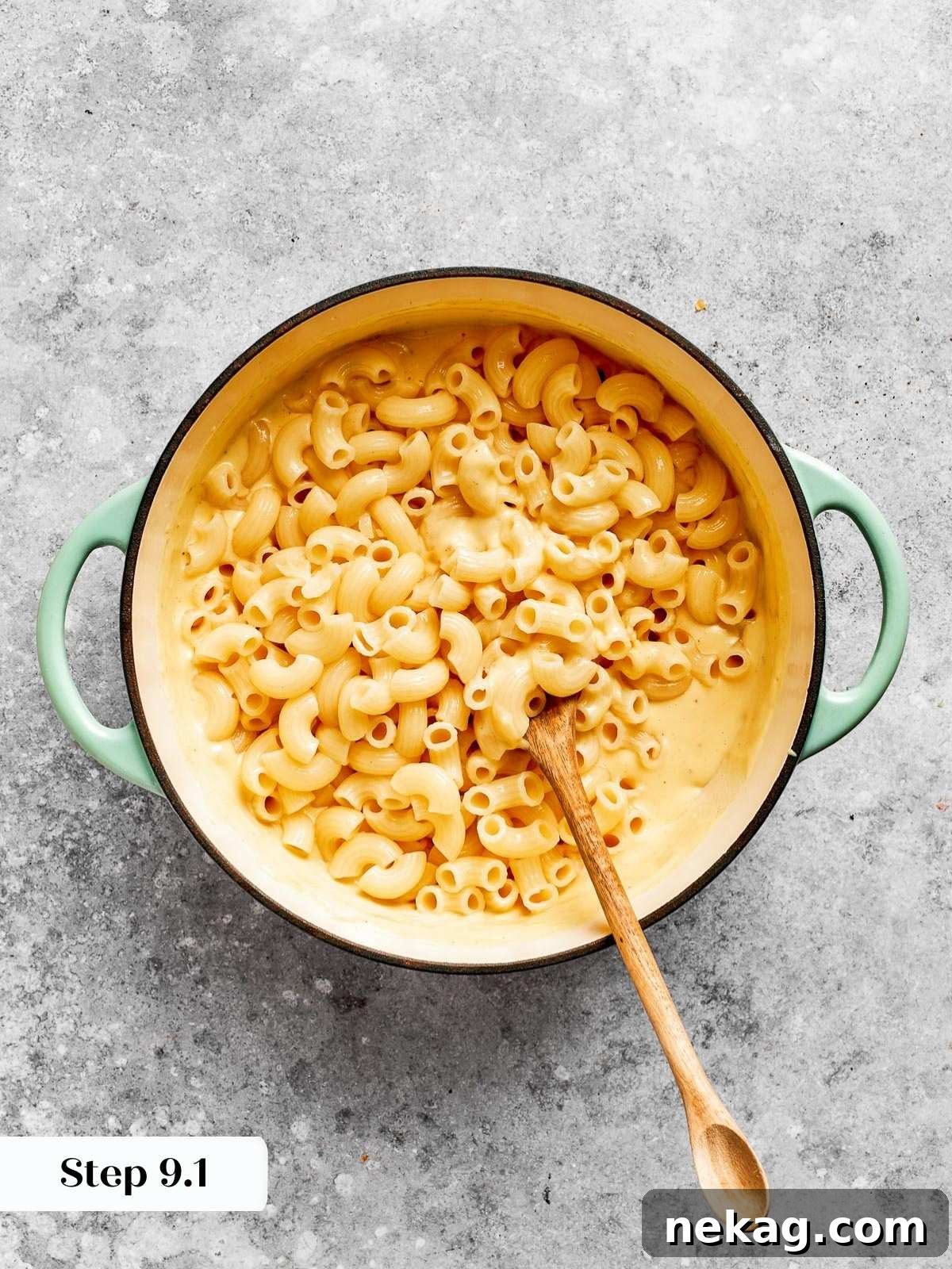 Ultimate Baked Mac and Cheese 14 Cooked elbow macaroni being stirred into a rich, creamy cheese sauce, ensuring every piece is coated in cheesy goodness.