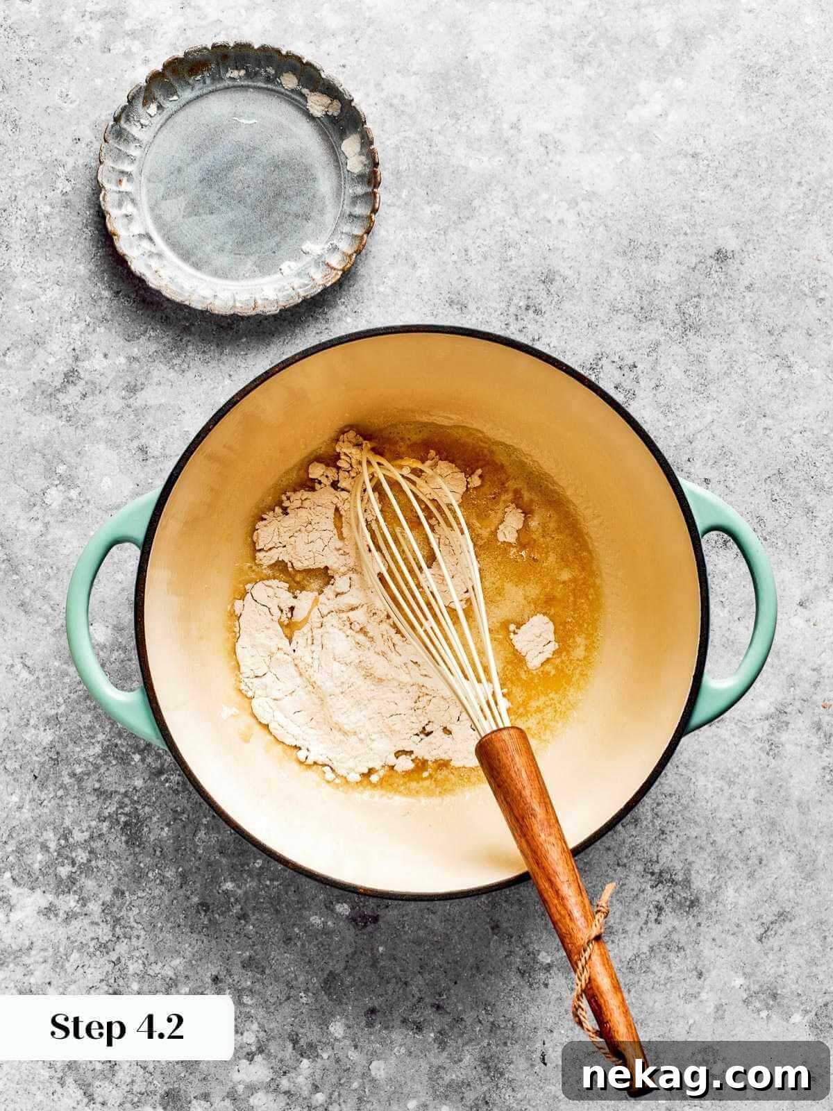 Ultimate Baked Mac and Cheese 7 All-purpose flour being whisked into melted butter in a saucepan, beginning the essential roux for a smooth mac and cheese sauce.