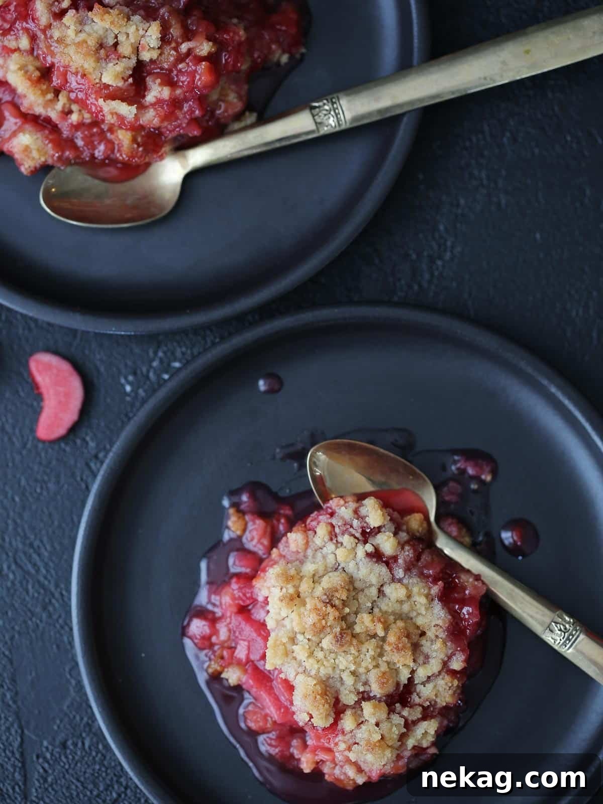 Tangy Raspberry Rhubarb Delight 4 A silver spoon next to raspberry rhubarb crisp with thick fruit filling, showing the perfect consistency and golden crumble.