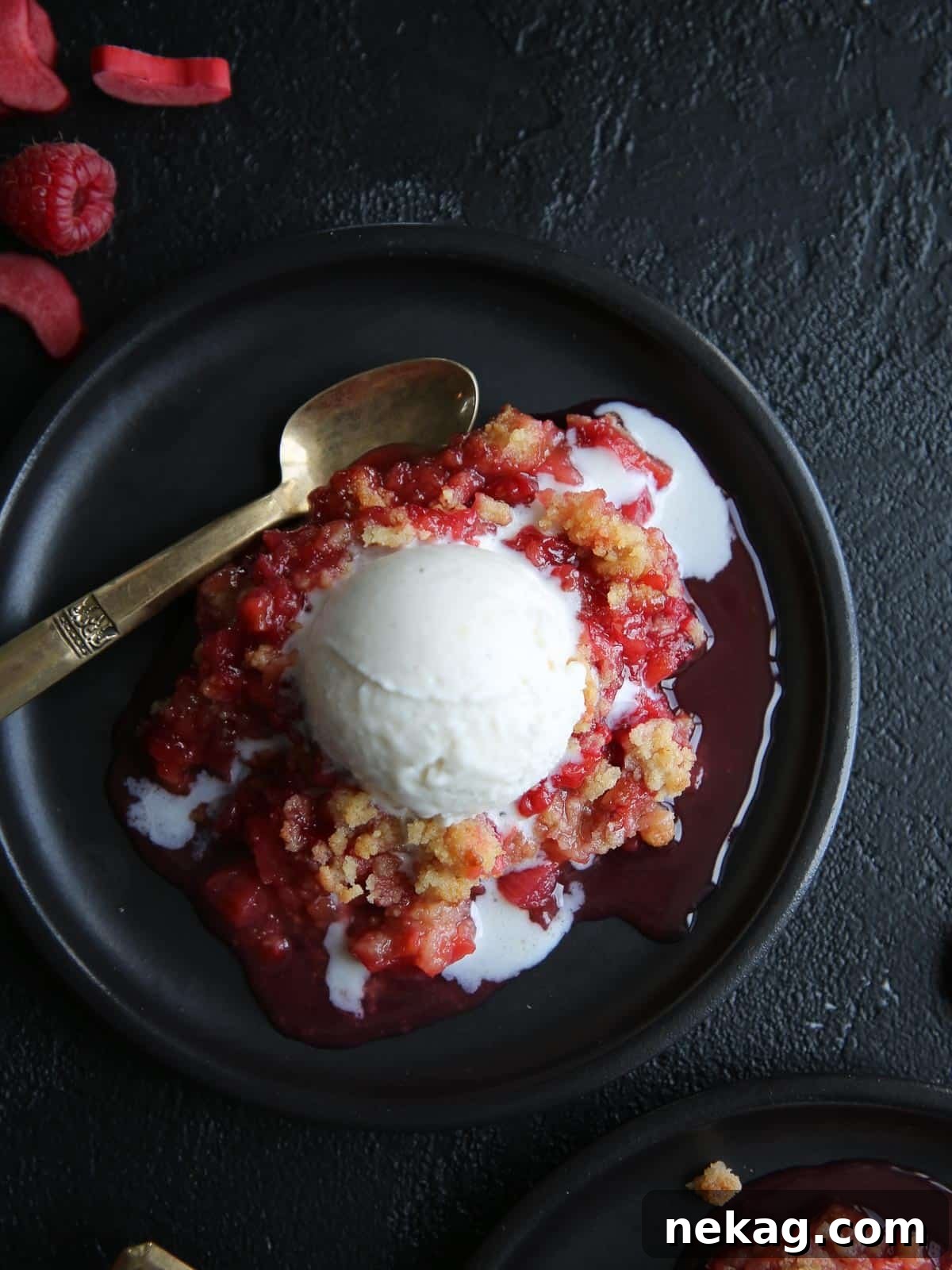 Tangy Raspberry Rhubarb Delight 5 Raspberry rhubarb crisp served on a black plate with a scoop of vanilla ice cream, ready to enjoy as a perfect dessert.