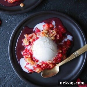 Grandmas Raspberry Rhubarb Crumble served on a black plate with a gold spoon.