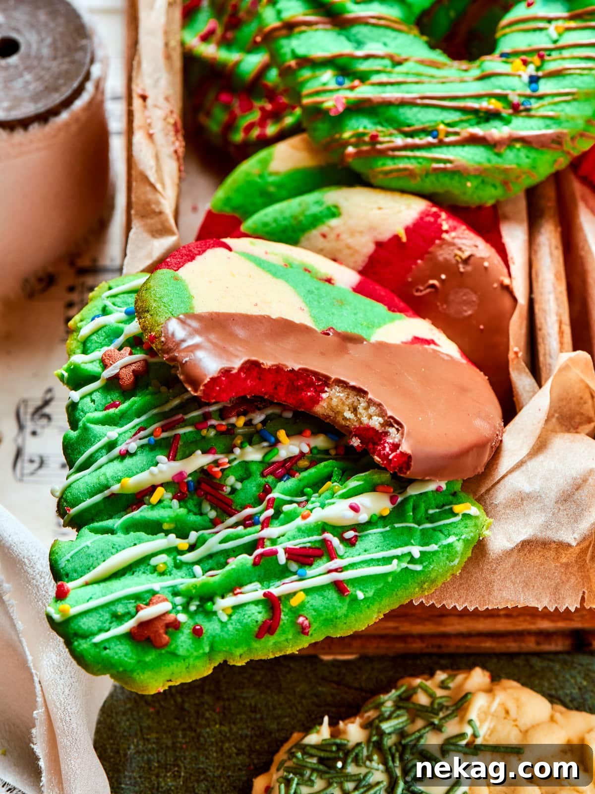 Chocolate-dipped spritz cookie with vibrant sprinkles and a small bite revealing its tender interior, showcasing its festive appeal.