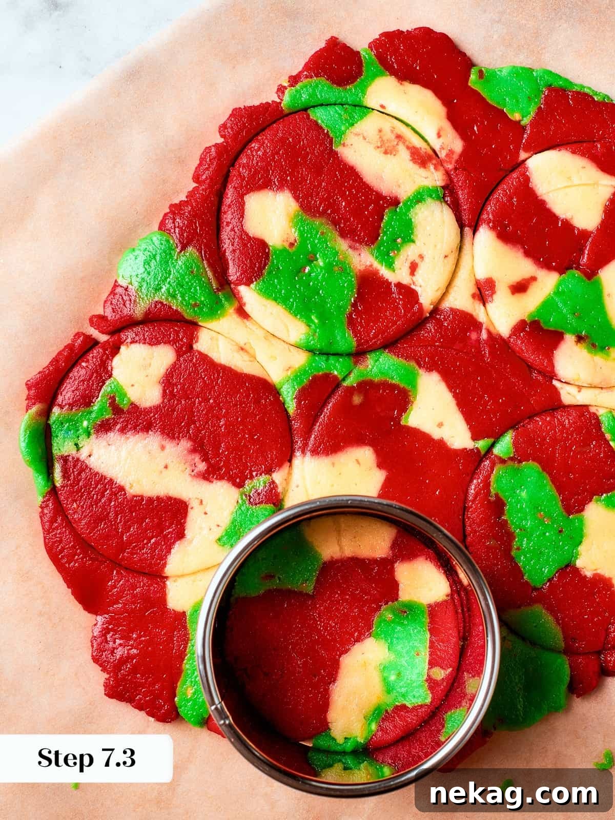 Green, red, and plain spritz cookie dough cut into festive shapes using cookie cutters, prepared for baking and colorful holiday presentation.