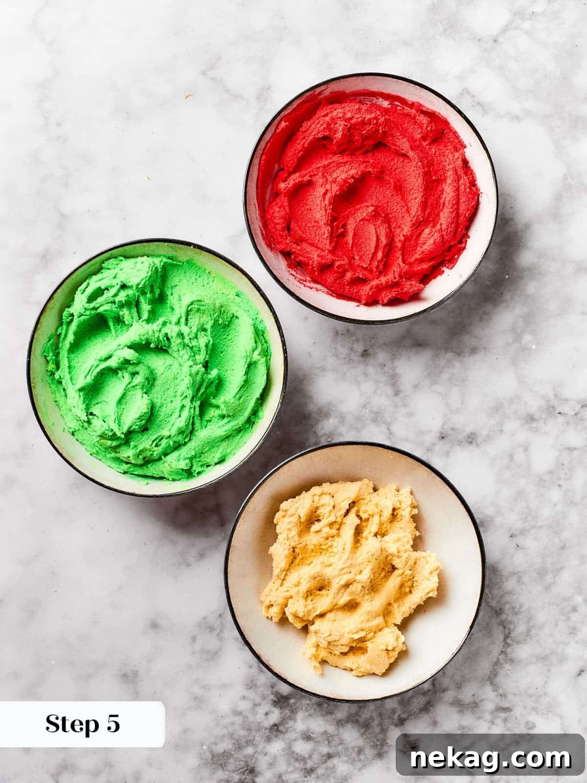 Cookie dough with vibrant red and green food coloring, ready for shaping into festive Christmas spritz cookies.