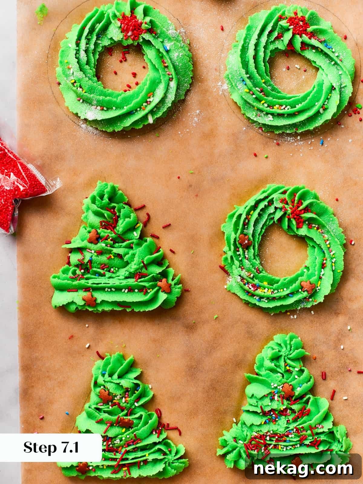 Piped wreath and Christmas tree shapes of spritz cookie dough neatly arranged on parchment paper, ready for baking.