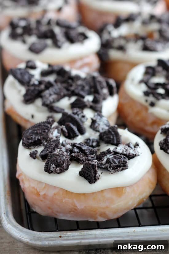 Close-up shot of two homemade Cookies and Cream Donuts with intricate frosting swirls and crushed Oreo pieces.